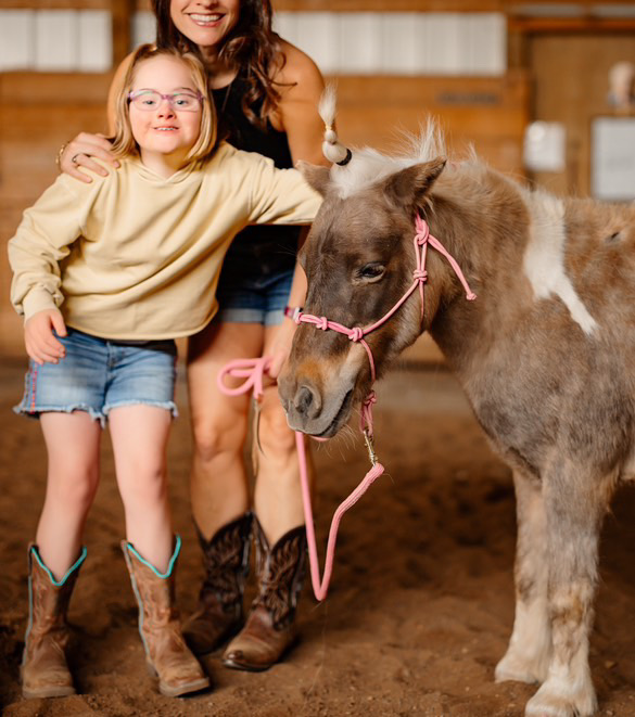 Photograph of a mother and young girl spending time with Sunflower the pony